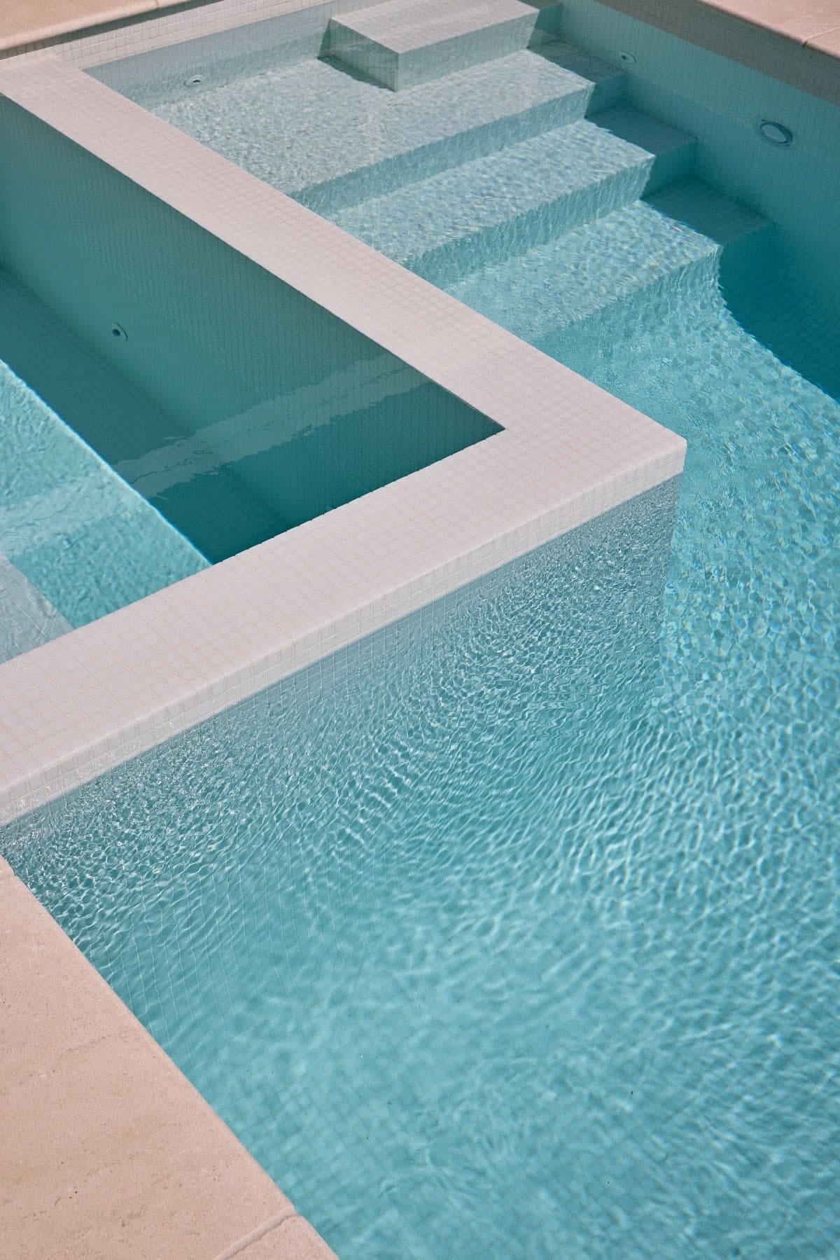 Close view of the spa's tiled spillway and submerged steps in pale mosaic tiling.