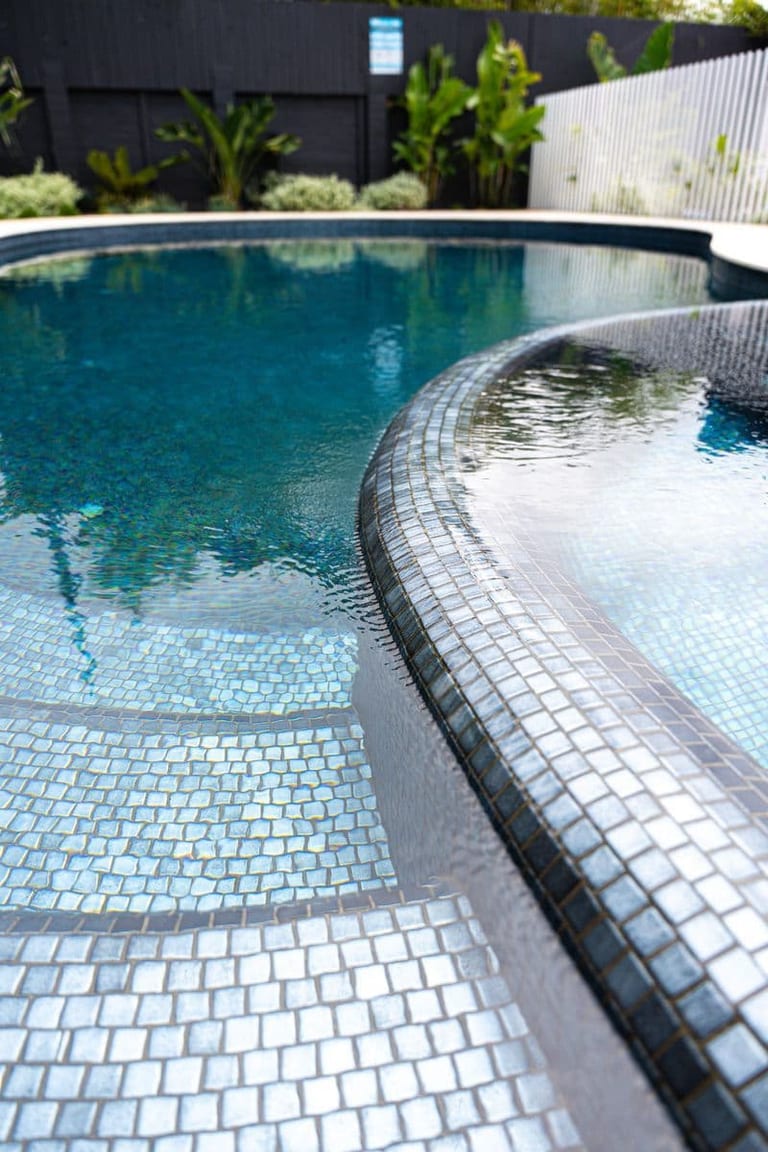 The sweeping mosaic edge between spa and pool, with the shallow shelf stepping away beneath.