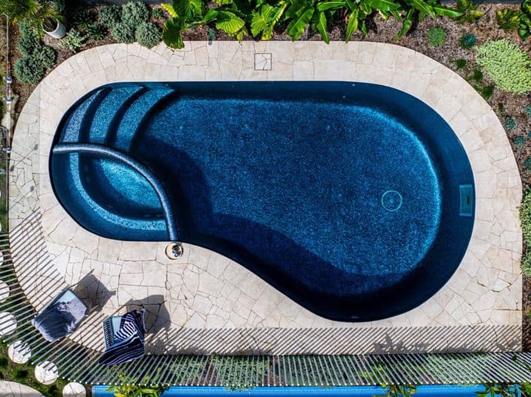 Straight-down aerial of the whole free-form pool, its spa, paving and surrounding garden beds.