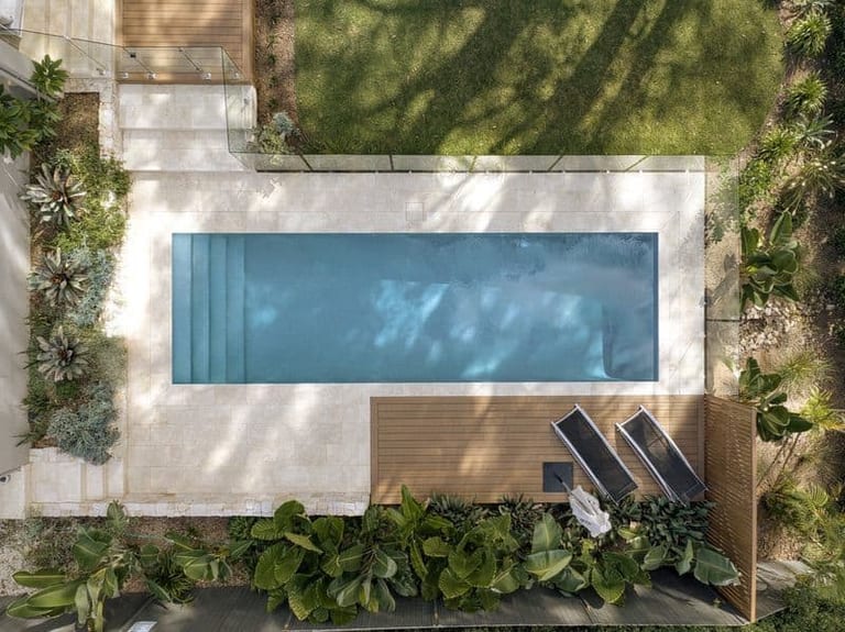 Straight-down view of the pool showing its full length, wide entry steps and the timber deck with two loungers.