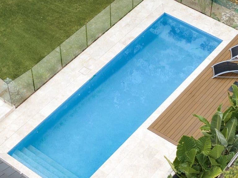 Looking down the length of the pool from above, lawn on one side and timber decking on the other.