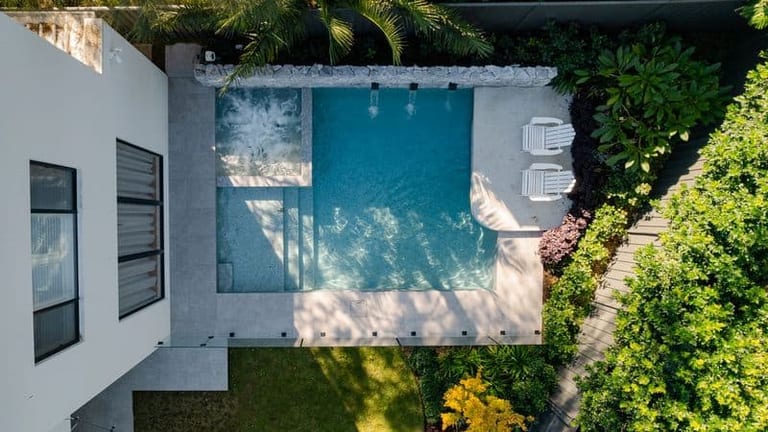 Straight-down aerial of the pool, its spa corner, paving and the house alongside.