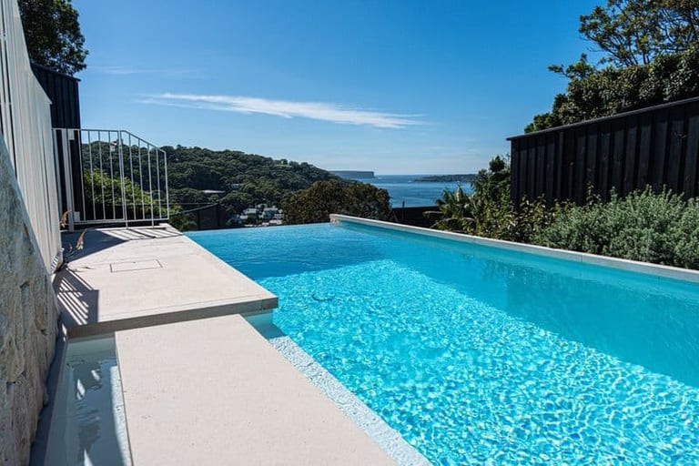 The pool from the house end, its edge dropping away toward the water and headland beyond.