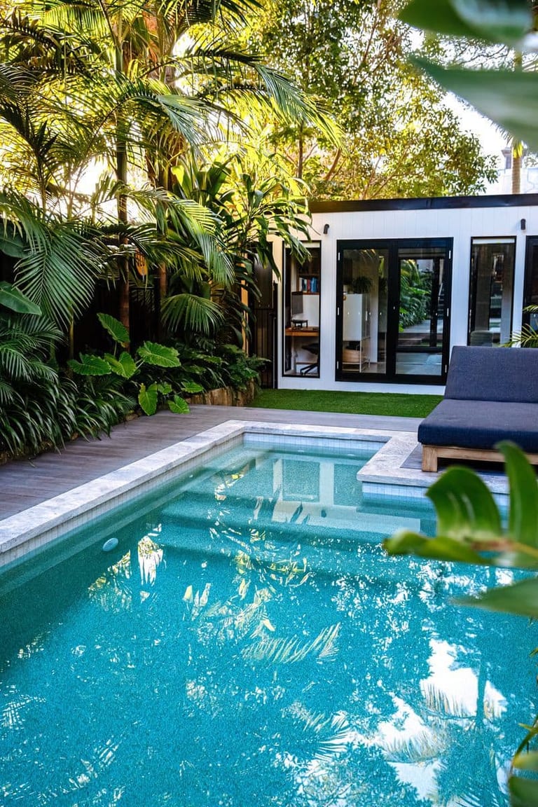 The pool's built-in bench and step, with the studio and daybed framed by palm fronds.