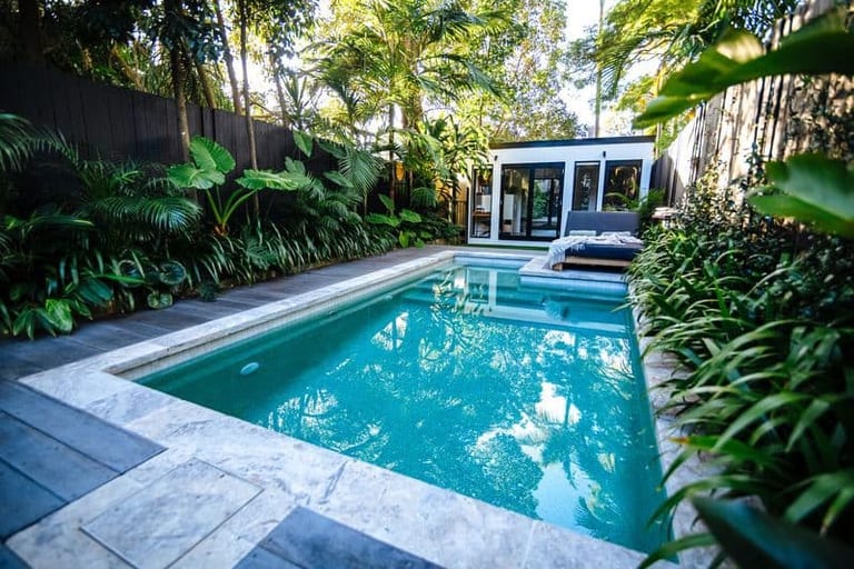 The full length of the courtyard pool, tropical planting either side and the studio ahead.