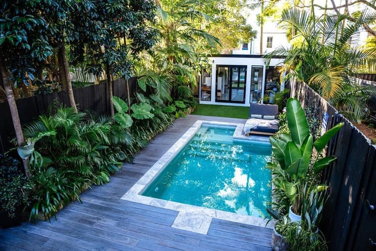 Elevated view down the narrow courtyard, the pool filling its width between deck and planting.