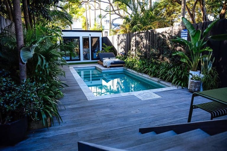 The pool and deck from the house steps, with the studio and daybed at the far end.