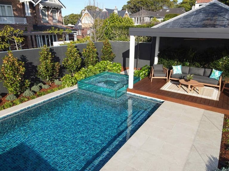 Elevated view of the pool and its glass spa, with a covered pavilion and lounge setting alongside.