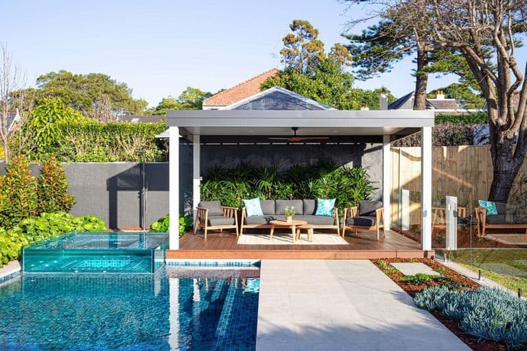 The pavilion and lounge setting seen across the pool, with the glass spa at left.
