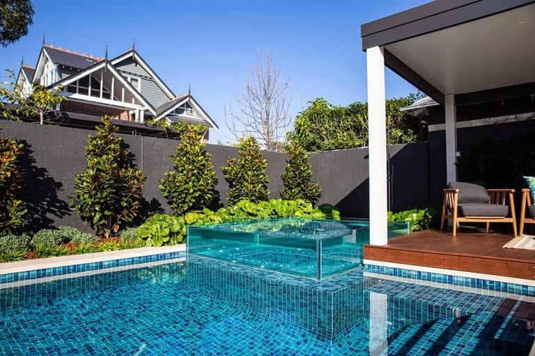 The glass spa raised in the pool, with heritage gables and the pavilion either side.