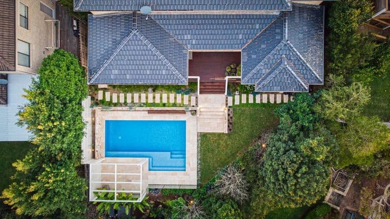 Straight-down aerial of the house, pool and pergola, with the garden stepping away on both sides.