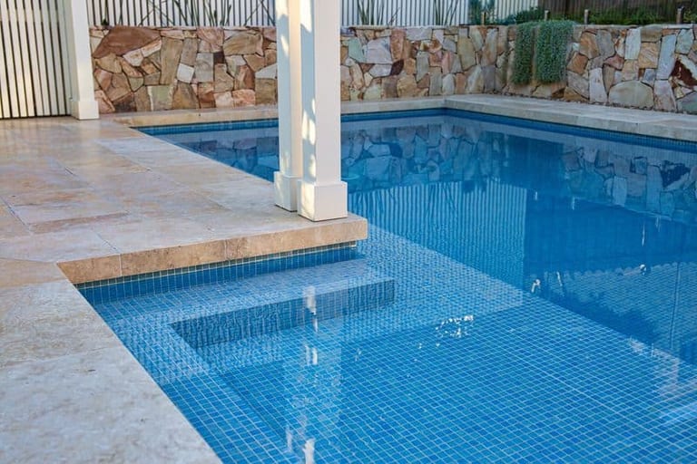 Detail of the pool's submerged bench and steps in blue mosaic, with the pergola post beside it.