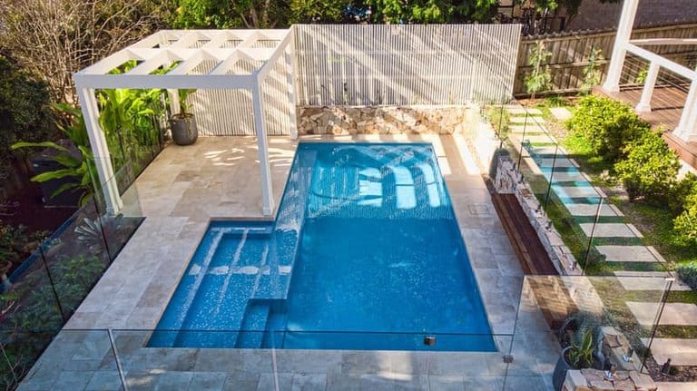 Aerial view of the pool and pergola, stepping stones and the tiled roof of the house alongside.