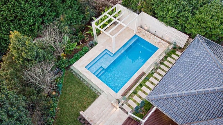 High aerial of the whole garden, pool and pergola set into the slope beside the house.