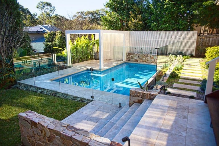 The whole pool terrace from above the lawn, pergola, screen and sandstone walls together.