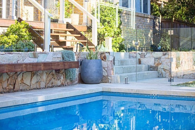 The pool, sandstone steps and timber bench, with the house stairs and verandah above.